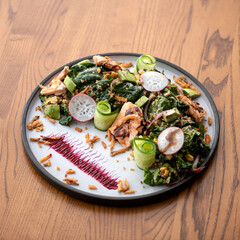 Plate of vegetarian salad on wooden table. Salad with spinach, mushrooms, vegetables, nuts and...
