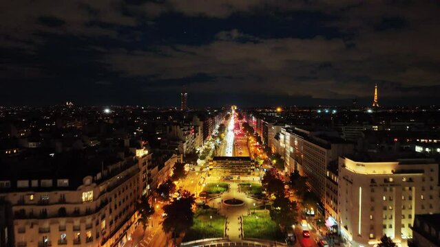 Stunning aerial shot from a boulevard in Paris, France in the night with the shining city lights and stunning cloudy sky