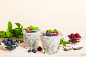 Healthy breakfast or morning with chia seeds vanilla pudding raspberry and blueberry berries on table background, vegetarian food, diet and health concept. Chia pudding with raspberry and blueberry