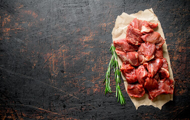 Sliced raw beef on paper with rosemary.
