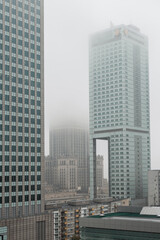 Obraz premium Beautiful modern foggy European city of Warsaw with office skyscrapers, business centers and a palace of culture with a fog. Urban cloudy day