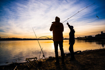 Father and son are fishing on winter day. River fishing. Teenage boy is learning to fish.
