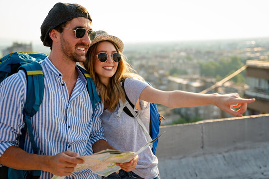 Happy couple on vacation sightseeing city with map. People travel fun honeymoon concept.