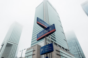 Modern business and office buildings in the foggy city Warsaw, Poland. Street with signs