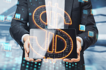 Close up of businessman hands holding tablet with glowing dollar sign on blurry office interior background. Finance, trade and money transfer concept. Double exposure.