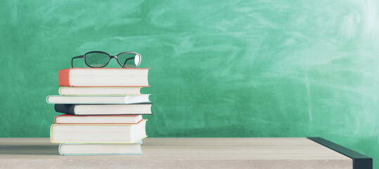 Education, learning and motivation concept with eyeglasses on stack of books on wooden table surface and chalkboard background. 3D rendering, mockup
