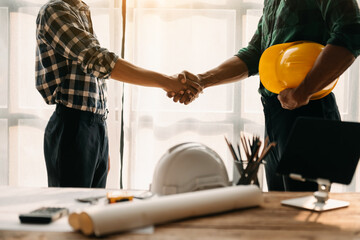 Construction team shake hands greeting start new project plan behind yellow helmet on desk in office center to consults about their building project... - obrazy, fototapety, plakaty