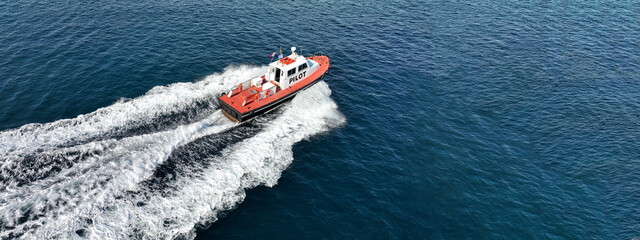 Aerial drone ultra wide photo of red pilot boat cruising in high speed in Mediterranean deep blue...
