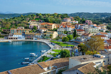 view of beautiful Kassiopi village – sea lagoon with calm turquoise water, cruise boats, colorful houses and street café