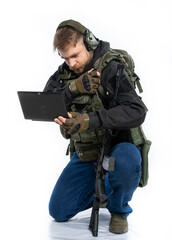 soldier, airsoft player in full gear works on a laptop in combat conditions. a man in headphones, a...