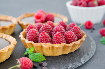 Delicious tart with chocolate cream and fresh raspberry on a gray background. Summer dessert. Copy space.