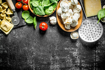 Different kinds of Italian raw pasta with tomatoes and spinach.