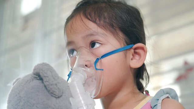 Kid girl making makes inhalation nebulizer steam sick cough at home, Asian Child using nebulizer mask equipment alone have smoke, stuffy nose and runny, oxygen spray inhaler therapy, Health medical