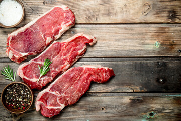 Raw marbled beef steaks with salt and aromatic spices.