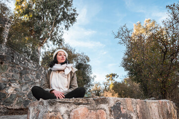 young tourist woman sitting on a big rock watching the landscape.