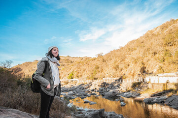 young caucasian tourist woman standing on the banks of a river