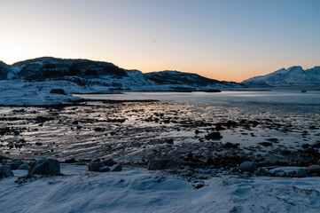 Wide angle landscape shot of the snow covered mountains and beach near Mjelle, part of the Bodo community in Arctic Norway, during the brief period of daylight in the arctic winter.