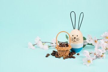 Wicker basket with roasted coffee beans, an easter bunny and cherry blossom, greeting card holiday,...