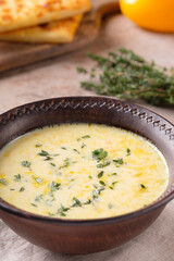 Cheese soup with thyme and yellow bell pepper on beige background close-up. Vegetarian food.