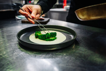 chef hand cooking broccoli with cheese sauce on restaurant kitchen