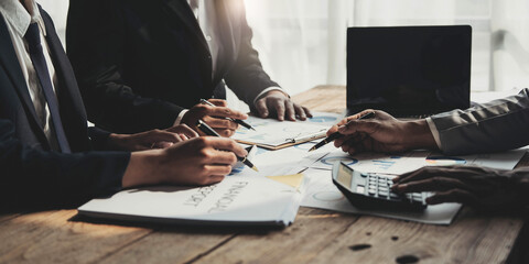 Business People Meeting using laptop computer,calculator,notebook,stock market chart paper for analysis Plans to improve quality next month. Conference Discussion Corporate Concept.