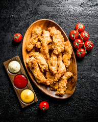 Chicken strips with sauces and tomatoes on a branch.