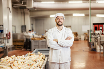 A happy meat industry worker is standing next to a container full of meat products and smiling at...