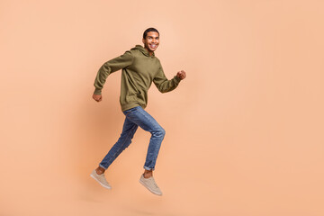 Fototapeta na wymiar Full length photo of cheerful man go store mall center low prices clothes products empty space isolated on beige color background