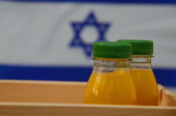 Plastic bottle with fresh juice. The flag of Israel is in the background. Concept: Israeli orange juice, Middle Eastern oranges