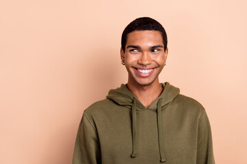 Photo of attractive funny man wear green khaki sweatshirt looking empty space isolated beige color...