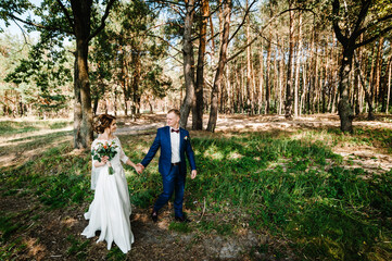 The groom and bride walking in the country. Portrait of the newlyweds in the park. Happy couple. Wedding photo. Couple in love.