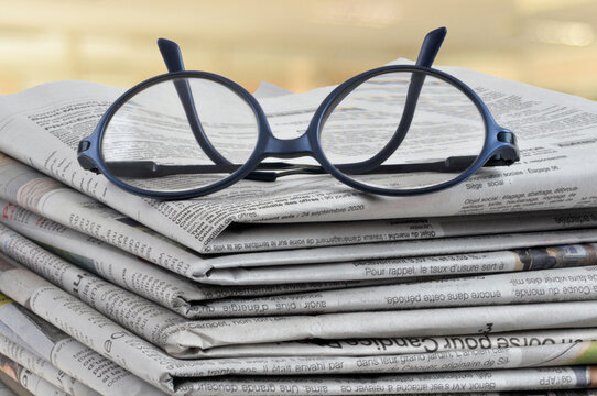 Lunettes pos&eacute;es sur une pile de journaux en gros plan