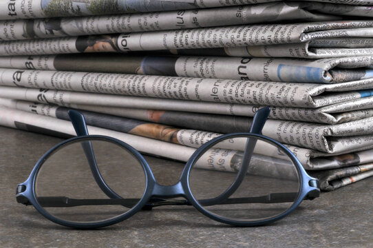 Lunettes avec une pile de journaux au second plan