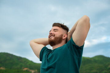 happy handsome free guy, young calm relaxed carefree man traveler with open raised hands enjoy...