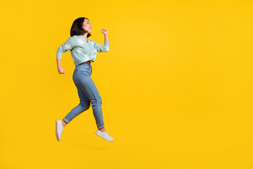Fototapeta na wymiar Full size side profile photo of cheerful girlish woman dressed blue pullover running look empty space isolated on yellow color background