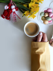 Bouquet of yellow daffodils with red and white martenitsa and a woman's hand holding a cup of coffee