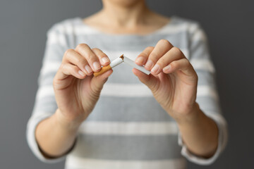 Portrait young woman holding broken cigarette in hands. Happy female quitting refusing smoking...
