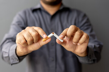 Portrait young man holding broken cigarette in hands. Happy male quitting refusing smoking...