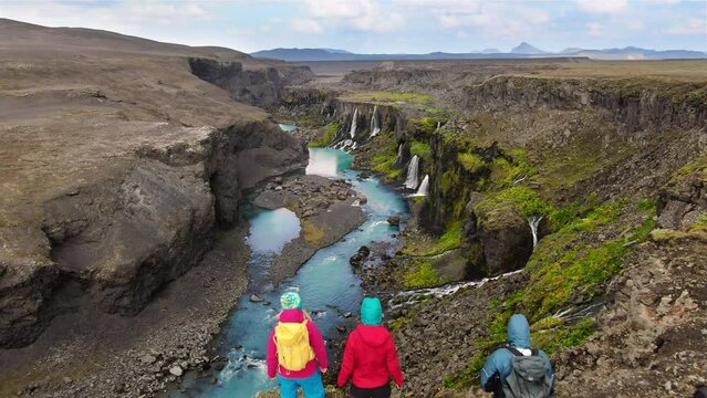 travel adventure group of people hiking in the nature aerial view,hikers on top of a mountain plateau looking at the scenic landscape,canyon with lots of watefalls and river