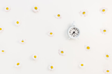 Clock on white with spring flowers background. Spring forward
