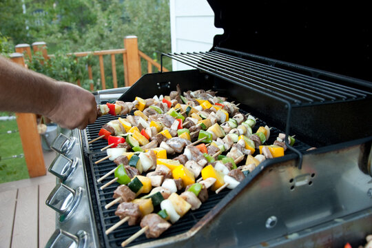 Meat and vegetable skewers cooking on a barbecue.