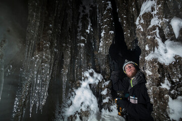 A young man admires delicate stalactites in an ice cave in Larsbreen, Svalbard.