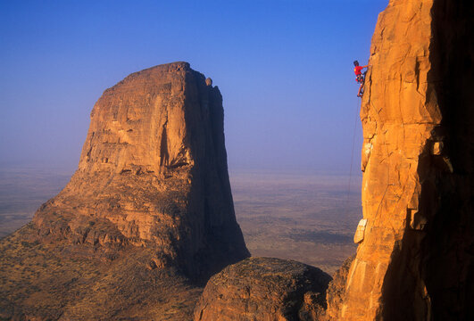 A man rock climbs the sandstone towers known as the Hand of Fatima in the Sahara Desert of Mali, West Africa.