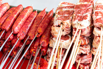Close-up of skewers of raw meat and sausages on a plate. 