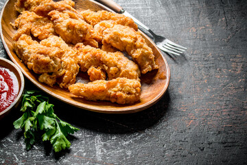 Chicken strips on a plate with greens and sauce.