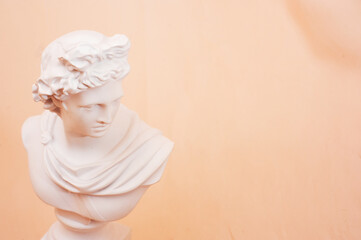 Statue of Apollo hovering on a beige background. Close up. 