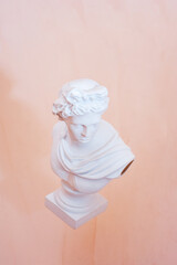 Statue of Apollo hovering on a beige background. Close up. copy space. isolated