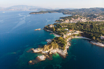 Obraz premium Aerial drone view of Kassiopi, village in northeast coast of Corfu island, Ionian Islands, Kerkyra, Greece in a summer sunny day, with marina, town, beach and castle