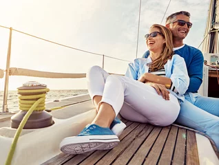 Fototapeten Smile, happy and couple on a yacht at sea, summer travel and ocean adventure in Spain. Peace, hug and man and woman on a boat for a luxury cruise, sailing and happiness on holiday on the water © Reese/peopleimages.com