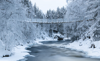 unfrozen river in a winter park, a suspension bridge over the river